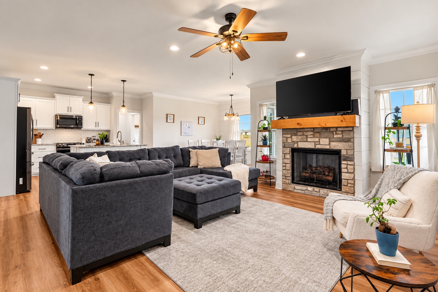 Open living room at 23 Cornerstone Dr with stone gas-log fireplace and kitchen beyond